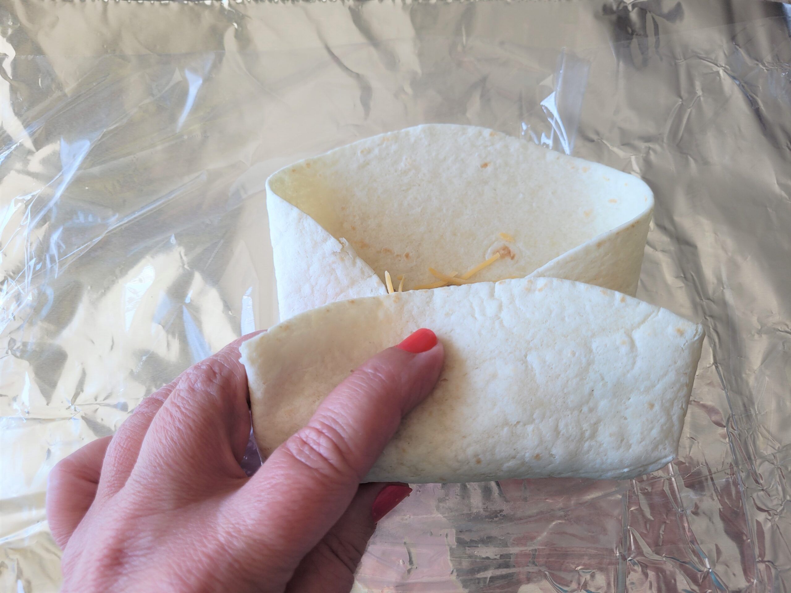 Fold in the sides, then fold the bottom over and behind the egg mixture, then roll to the top.