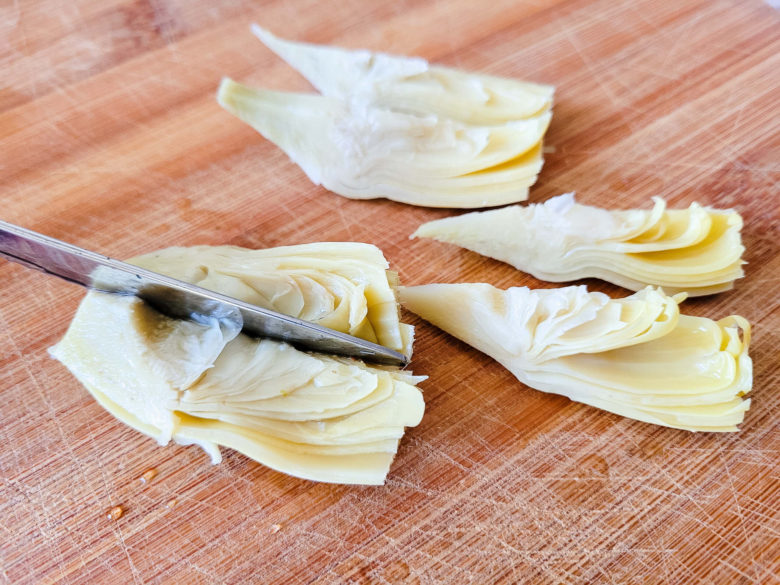 Quarter the artichoke hearts, then slice each quarter in half.